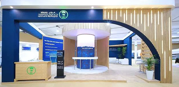 جناح المركز الوطني لإدارة النفايات (MWAN): مدخل أزرق يعلوه قوس منحنٍ من شرائح الخشب، وأسطوانة عرض دائرية، ومكتب استقبال