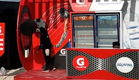 منصة راعٍ حمراء في التفعيل الشاطئي للوطنية للتأمين، وخلف مكتبها الذي يحمل العلامة ثلاجات مشروبات